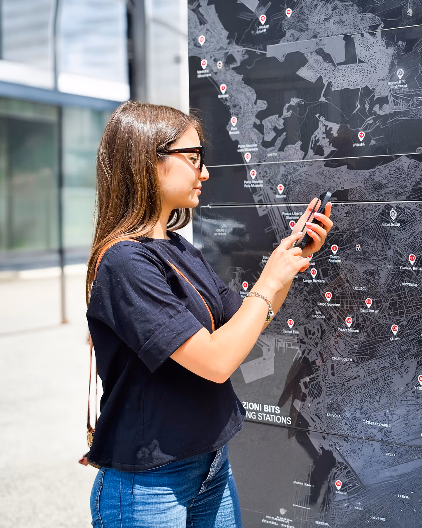 Ragazza che consulta l'app weelo vicino ad un totem bits con la mappa delle ciclostazioni